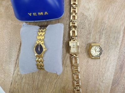 a watch and a bracelet on a table next to a blue purse
