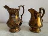 two gold pitchers sitting next to each other on a table