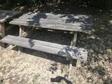a picnic table with a bench in the middle of a field