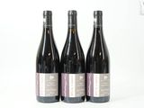 trois bouteilles de vin posées les unes à côté des autres sur une surface blanche