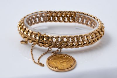 a close up of a gold bracelet with a coin on it