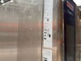 a stainless steel refrigerator in a warehouse with a sign on the door