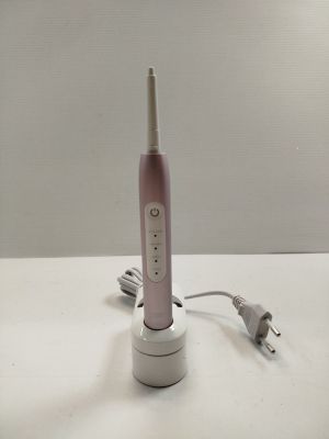 une brosse à dents électrique rose posée sur une table blanche
