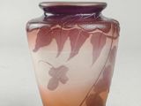 a purple vase with leaves on it sitting on a table