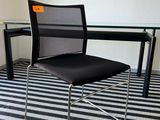une chaise noire placée devant une table en verre