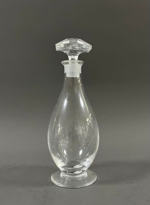 flacon de parfum en verre transparent muni d'un bouchon transparent, posé sur un support gris