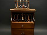une armoire en bois surmontée d'une série de porte-pipes