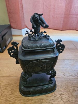 a bronze statue of a bird sitting on top of a bowl