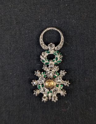 a close up of a diamond and emerald broocher on a black cloth