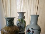 three vases sitting on a table with a curtain in the background