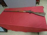un vieux fusil en bois posé sur une table rouge recouverte d'une nappe rouge