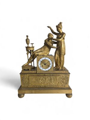 une horloge posée sur une table, sur laquelle se trouve une statue