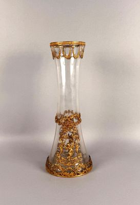 a glass vase with gold decoration on it on a white surface