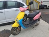 brightly colored motor scooter parked in front of a white car