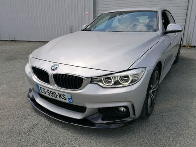 La BMW argentée est garée devant un immeuble.