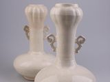 two white vases sitting on a table with a gray background