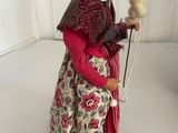 a figurine of an old woman holding a bird on a stick