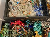 an open box filled with lots of different colored beads and necklaces
