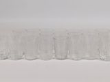 six clear glasses lined up in a row on a white surface