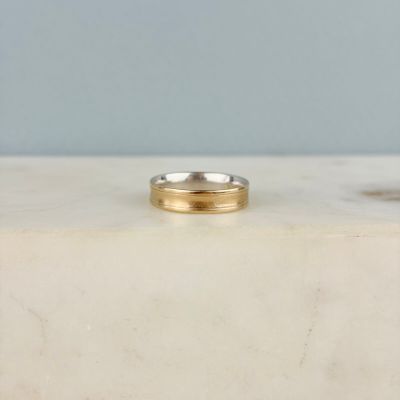a close up of a gold wedding ring on a marble surface