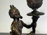 bronze statue of a man holding a candelier on a black table