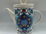a white tea pot with a blue and yellow design on it