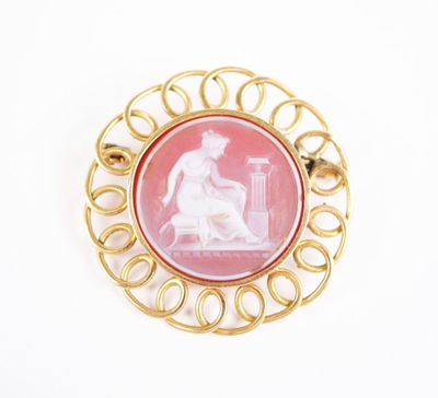 an image of a pink and gold broochle with a woman sitting on a bench