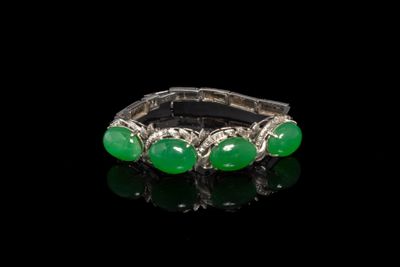 un gros plan d'une bague ornée de pierres vertes sur un fond noir