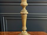 an antique brass candle holder on a wooden table with a blue wall in the background