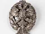 a silver brooch with a coat of arms and a crown on it