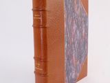 a small book with a brown cover sitting on a white surface