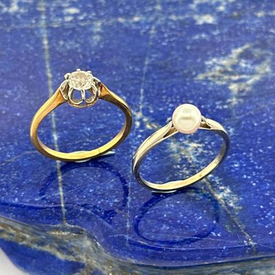 pair of gold and silver rings with a pearl on a blue marble slab