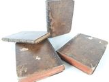 three old books stacked on top of each other on a white surface