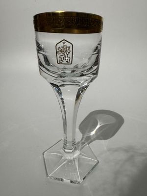 un verre à vin orné d'un bord doré posé sur une table