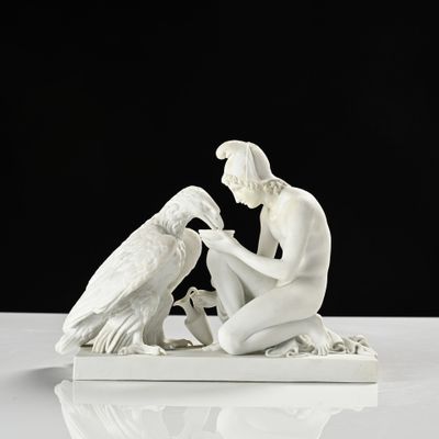 une statue blanche représentant un homme et un oiseau, posée sur une table