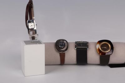three watches on display on a white display stand