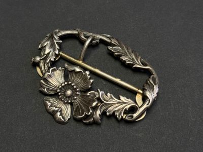 un gros plan sur une broche en argent ornée de fleurs et de feuilles