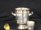 a silver ice bucket and spoon on a black background