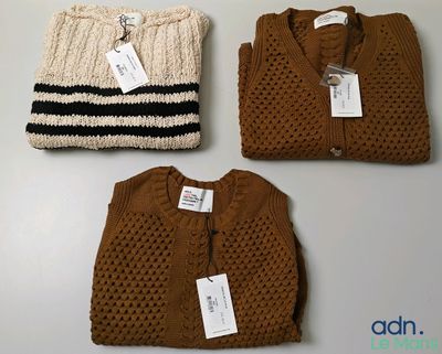 three sweaters and a cardigan are on display on a table