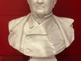 white marble bust of a man in a suit on a red surface