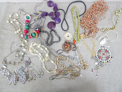 many different necklaces and bracelets laid out on a table