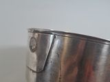 a silver bowl with a metal handle on a table