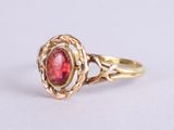 a close up of a gold ring with a red stone in it