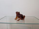 une figurine de grenouille brune posée sur une étagère en verre