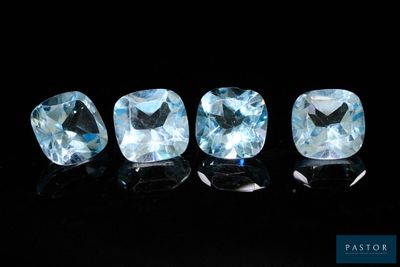 un ensemble de trois pierres précieuses de topaze bleue posées sur une surface noire