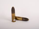 two bullet shells on a white surface with one bullet in the foreground