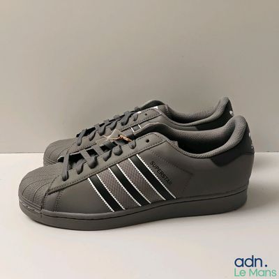 a close up of a pair of grey adidas sneakers on a white surface