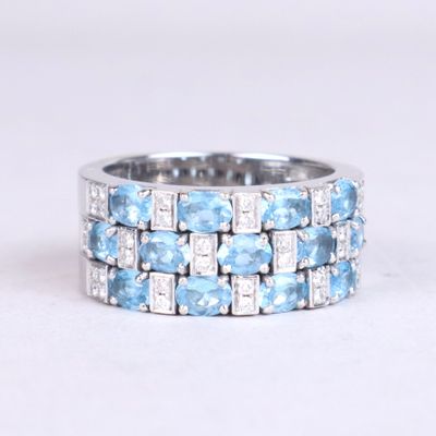 a close up of a blue and white diamond ring on a white surface