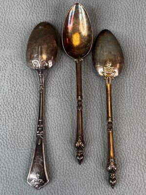 three silver spoons and two silver spoons sitting on a table