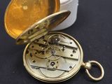 une petite montre de poche en or dans une boîte blanche
